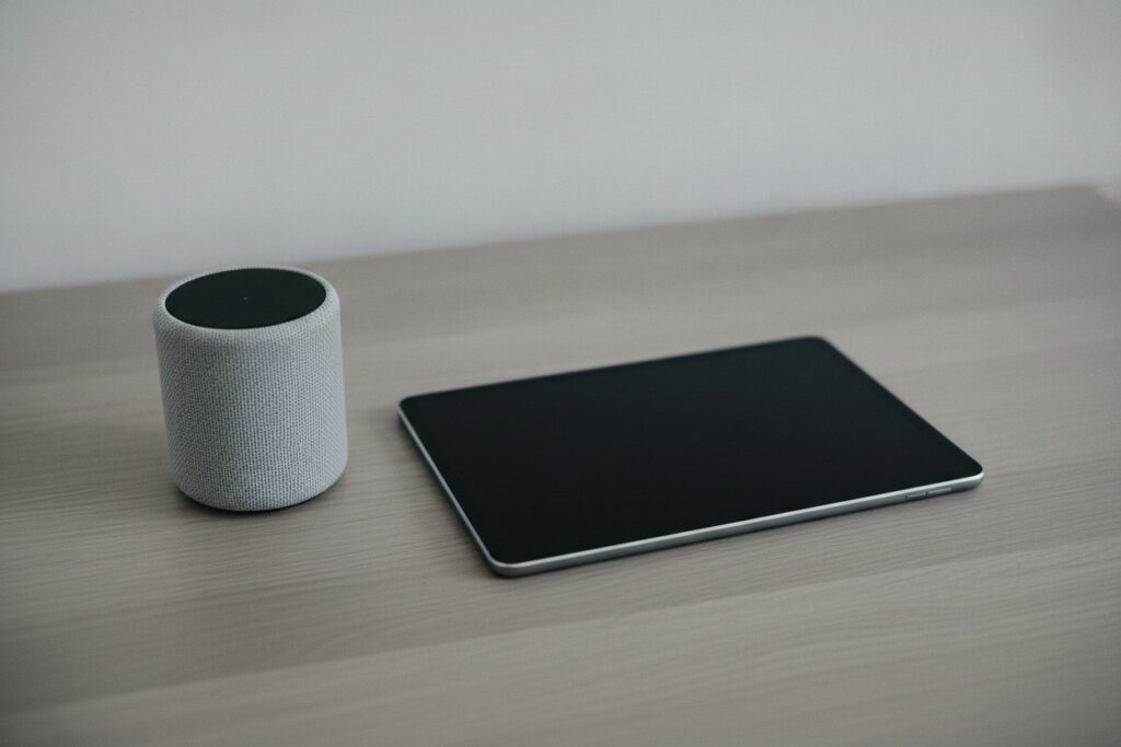 Enceinte connectée et tablette posées côte à côte sur une table en chêne clair