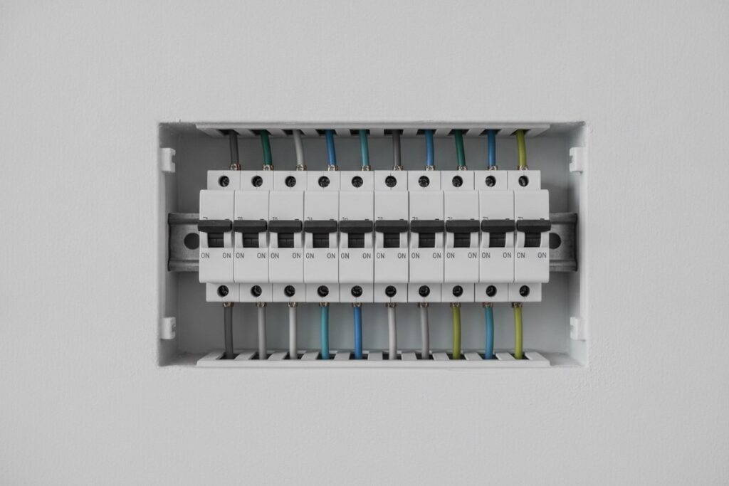Rangée de disjoncteurs modulaires blancs sur rail dans un tableau électrique ouvert