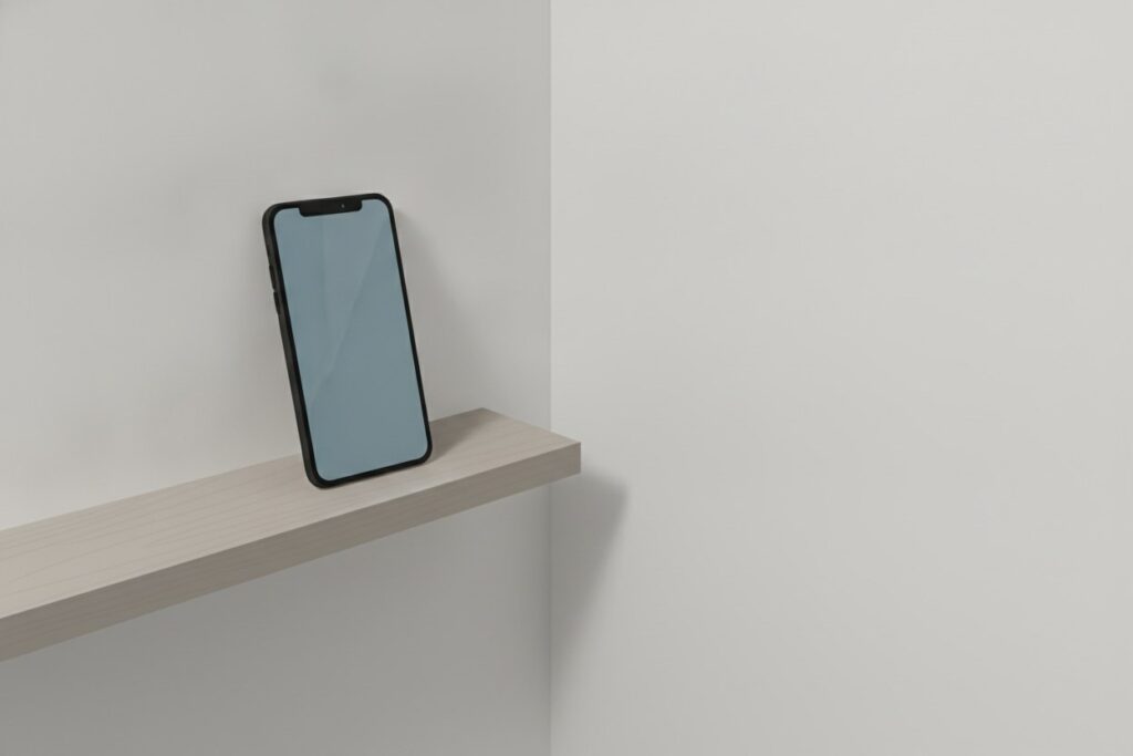 Téléphone posé à plat sur une tablette en bois clair dans un couloir, écran allumé